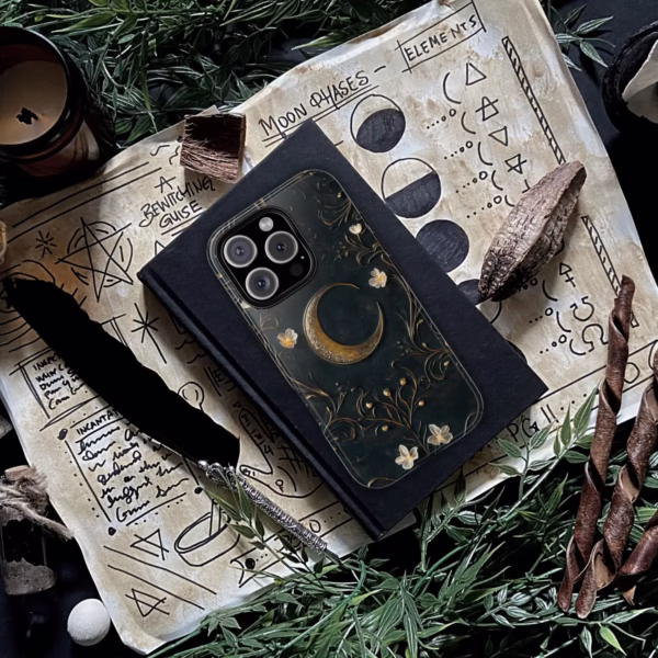 The phone case rests atop spell pages, herbs, and a journal, emphasizing its tomecore and witchy aesthetic.